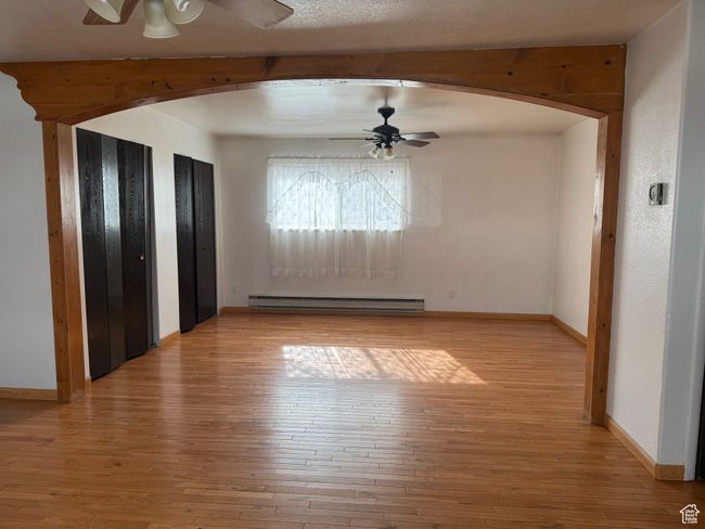 Interior space featuring arched walkways, baseboards, light wood finished floors, and baseboard heating | Image 10