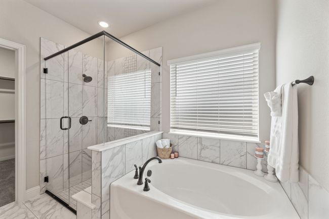 Bathroom featuring a garden tub, a marble finish shower, marble look tile flooring, and a walk in closet | Image 16