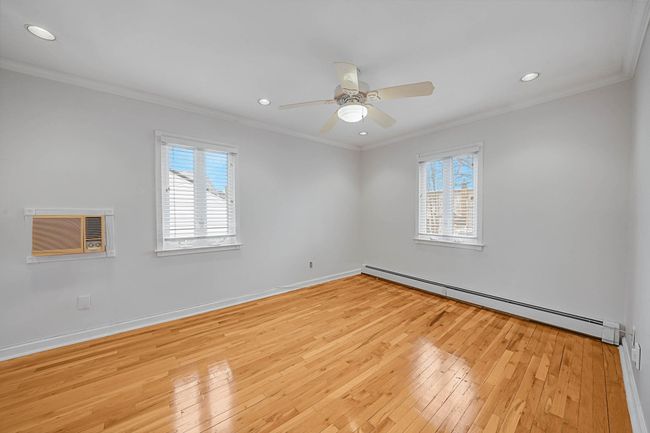 Spare room featuring a baseboard radiator, ornamental molding, and light wood-type flooring | Image 15