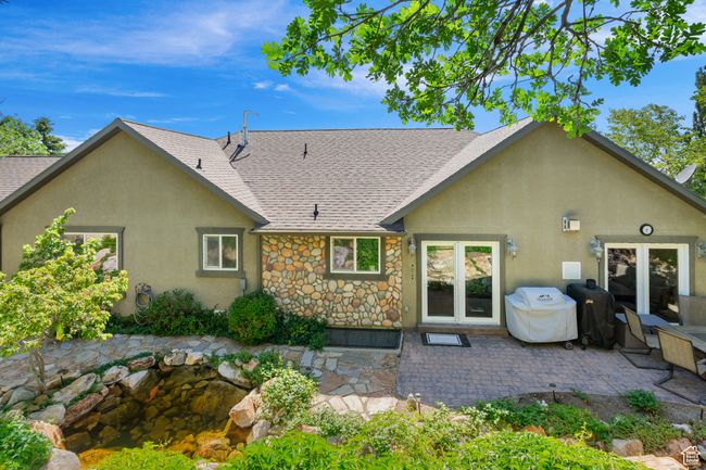 Back of house featuring a shingled roof, stucco siding, a patio, and stone siding | Image 37