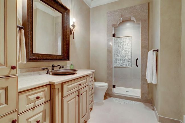 First bedroom bathroom with walk in shower, limestone counters and copper sink. | Image 30