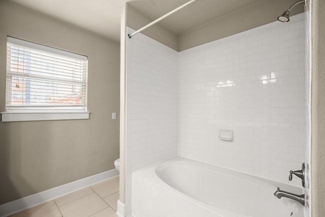 Bathroom with tile patterned floors, baseboards, toilet, and washtub / shower combination | Image 16