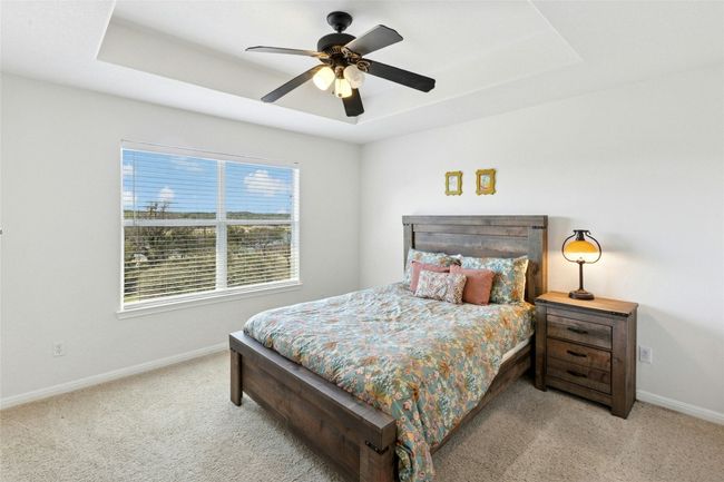 Carpeted bedroom with a raised ceiling and a ceiling fan | Image 19