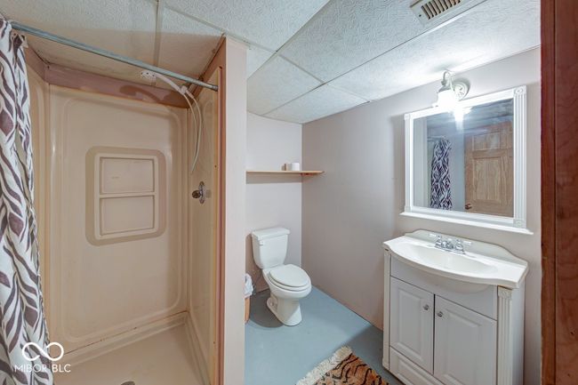 bathroom featuring a shower with shower curtain, vanity, a drop ceiling, and concrete floors | Image 22