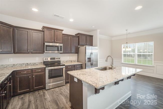 Kitchen view of granite countertops, stainless steel appliances, and extended island | Image 8