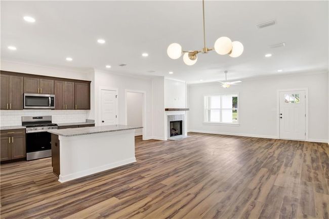 Kitchen with ornamental molding, decorative backsplash, a kitchen island, dark wood-style floors, and appliances with stainless steel finishes | Image 16