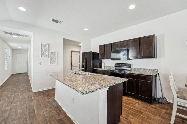 Kitchen featuring black appliances, dark wood-style floors, visible vents, and a sink | Image 8