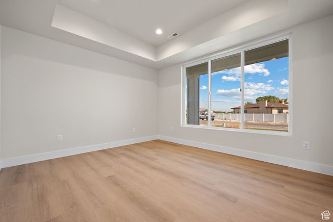 Unfurnished room with light wood-style floors, a raised ceiling, and recessed lighting | Image 5