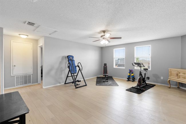 Exercise room featuring a ceiling fan, a textured ceiling, and light wood-style floors | Image 17