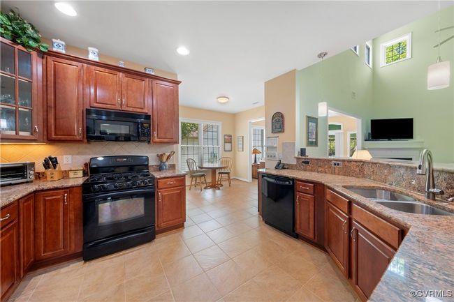 Kitchen with black appliances, decorative backsplash, light stone counters, and recessed lighting | Image 18