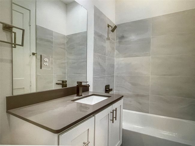 Full bath featuring washtub / shower combination, tile walls, and vanity | Image 5