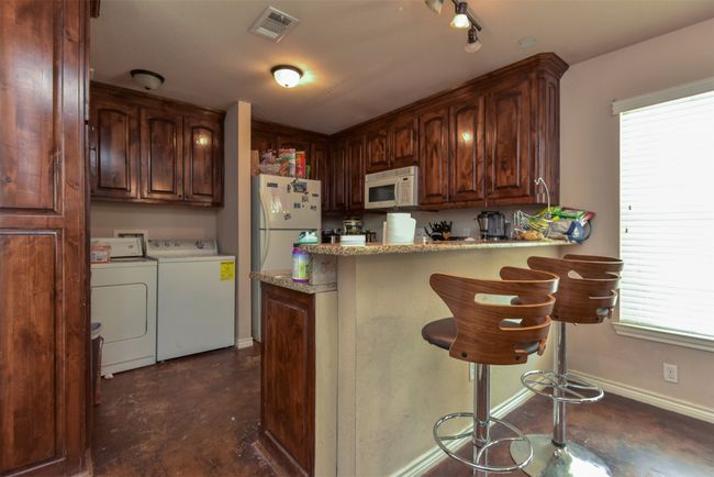 Kitchen featuring white appliances, washer and clothes dryer, a wealth of natural light, and kitchen peninsula | Image 4