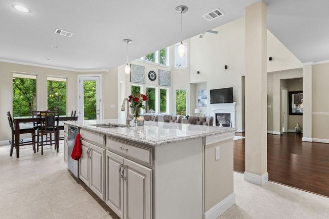 Kitchen featuring a sink, dishwasher, plenty of natural light, a kitchen island with sink, and crown molding | Image 11