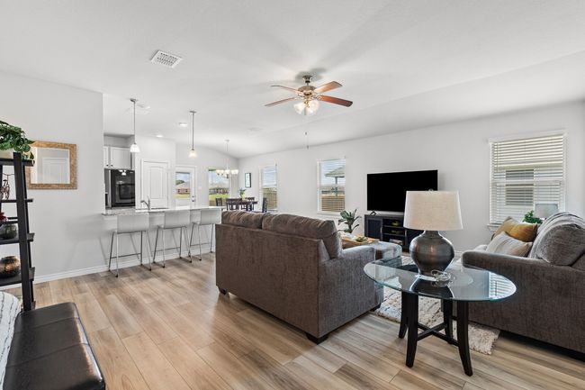 Living room featuring light wood-style floors, ceiling fan, and a chandelier | Image 13