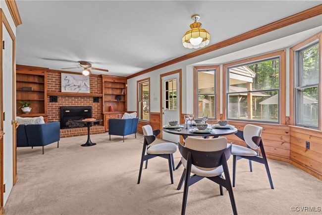 Dining area with ornamental molding, light colored carpet, ceiling fan, a fireplace, and built in shelves | Image 7