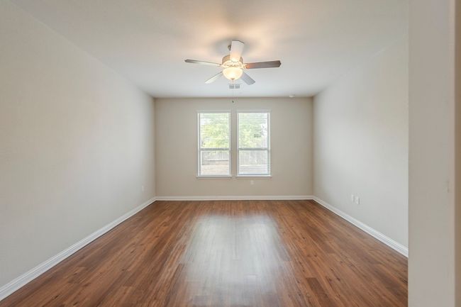 Empty room featuring a ceiling fan, baseboards, visible vents, and dark wood-style floors | Image 12