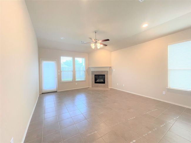 Unfurnished living room featuring a ceiling fan, light tile patterned flooring, a glass covered fireplace, and recessed lighting | Image 7