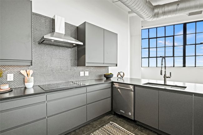 Kitchen featuring a sink, dark countertops, wall chimney exhaust hood, gray cabinetry, and dishwasher | Image 19