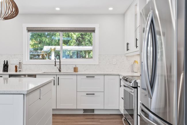 Kitchen with stainless steel appliances, white cabinetry, a sink, and light stone counters | Image 15