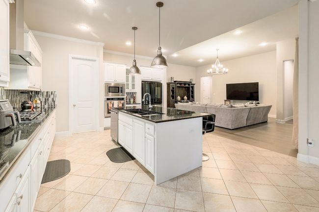 Kitchen featuring light tile patterned flooring, a chandelier, stainless steel appliances, recessed lighting, and open floor plan | Image 12