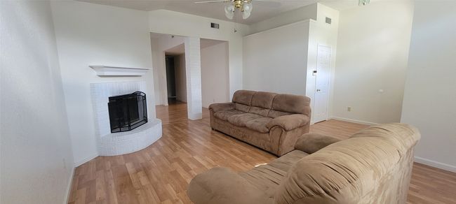 Living area with light wood-style flooring, ceiling fan, baseboards, and a fireplace | Image 4