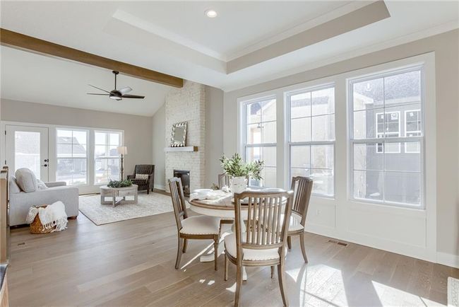 Dining space featuring light wood-type flooring, a healthy amount of sunlight, ceiling fan, and a stone fireplace | Image 5
