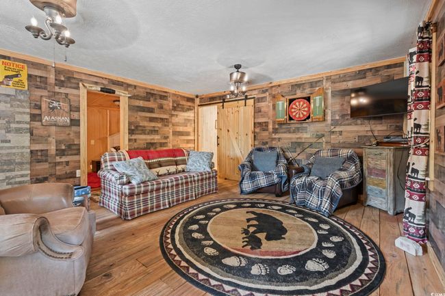 Living area with wood walls, hardwood / wood-style floors, and a barn door | Image 16