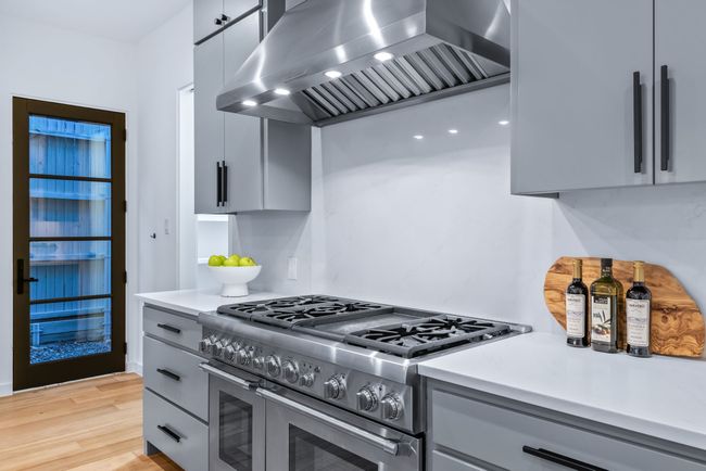 Kitchen with double oven range, extractor fan, gray cabinetry, light countertops, and light wood-type flooring | Image 12