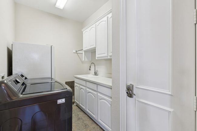 This spacious laundry room is a dream! Besides room for a full size washer and dryer, you have room for a freezer or second refrigerator, great storage, counterspace for folding clother, sink, drip dry bar, storage closet and a dog wash! Fantastic! | Image 28