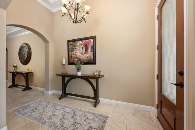 Foyer featuring ornamental molding, arched walkways, and a chandelier | Image 6
