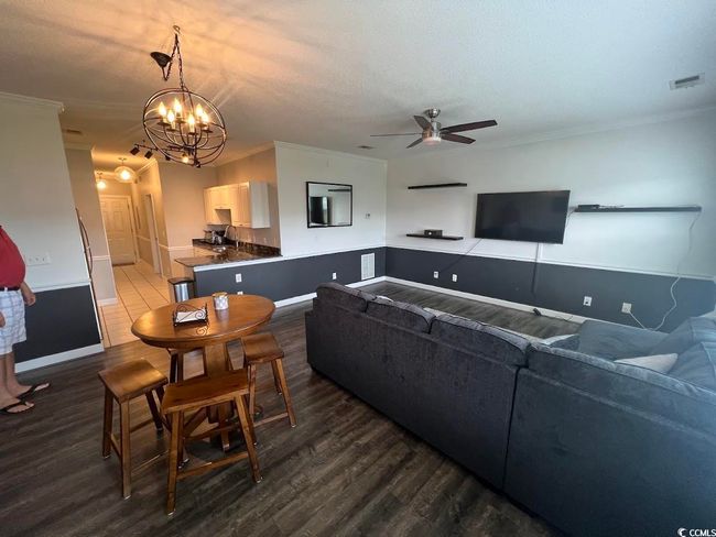 Living area featuring a ceiling fan, dark wood-style flooring, a textured ceiling, a chandelier, and crown molding | Image 5