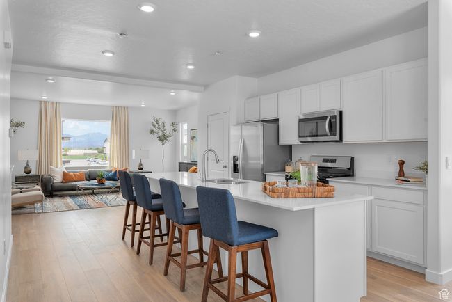 Kitchen featuring stainless steel appliances, a breakfast bar area, an island with sink, light countertops, and recessed lighting | Image 7