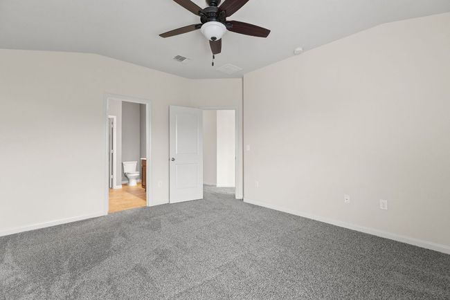 Unfurnished bedroom with carpet flooring, vaulted ceiling, baseboards, connected bathroom, and ceiling fan | Image 9