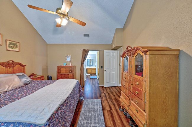 Expansive primary bedroom featuring high ceilings and elegant engineered wood floors. | Image 20