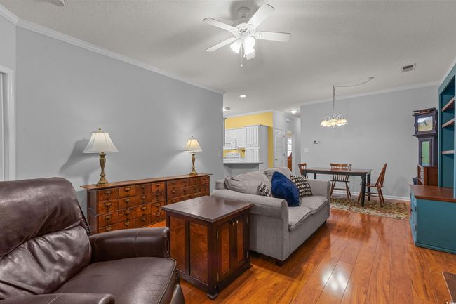 Living area featuring crown molding, wood-type flooring, a ceiling fan, baseboards, and a chandelier | Image 19