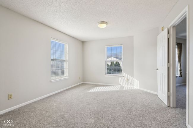 carpeted empty room featuring plenty of natural light, a textured ceiling, and baseboards | Image 37