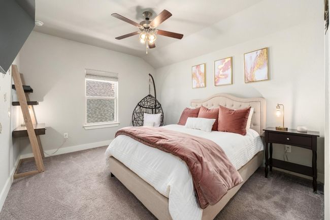 Upstairs carpeted bedroom featuring a ceiling fan, a walk in closet and vaulted ceiling. | Image 29