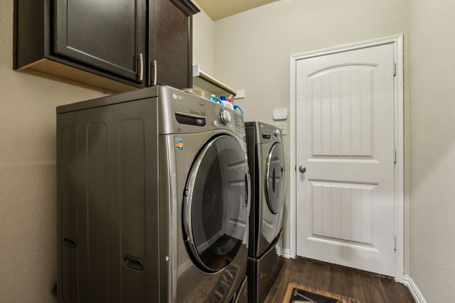 Washroom with cabinet space, separate washer and dryer, dark wood-style flooring, and baseboards | Image 18