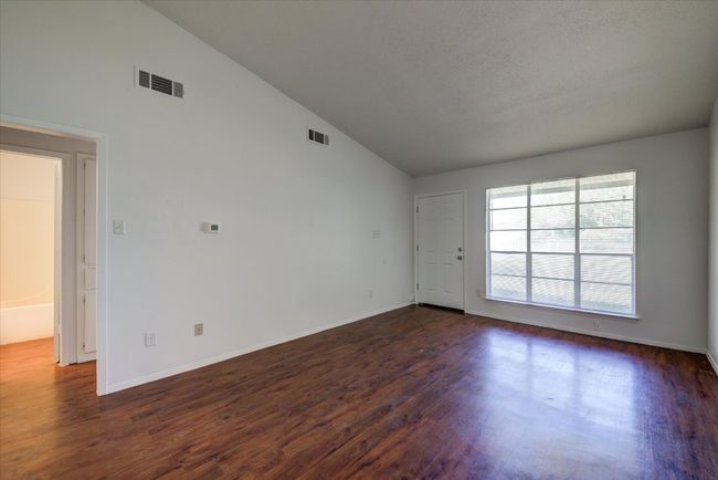 Spare room featuring high vaulted ceiling, dark wood-style floors, and visible vents | Image 6