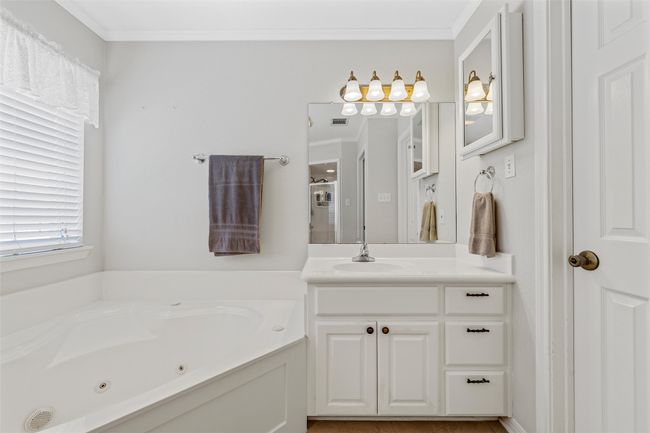 Full bathroom with ornamental molding, a tub with jets, vanity, and visible vents | Image 21