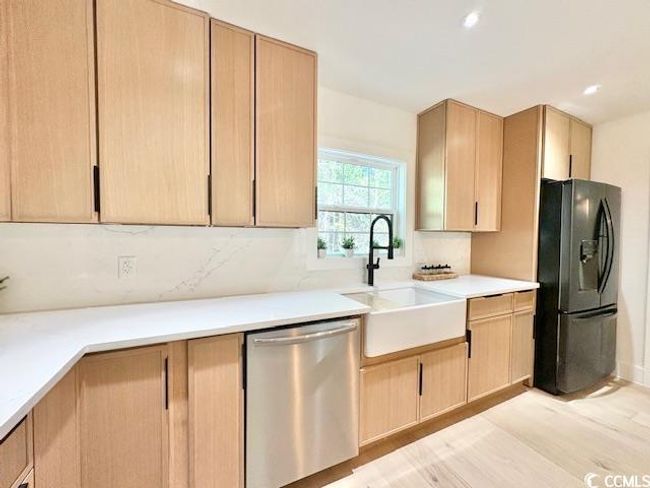 Kitchen featuring stainless steel dishwasher, black refrigerator with ice dispenser, light brown cabinetry, and recessed lighting | Image 11