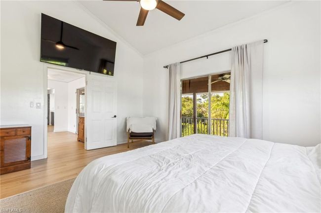 Bedroom featuring ceiling fan, wood finished floors, high vaulted ceiling, and access to exterior | Image 21