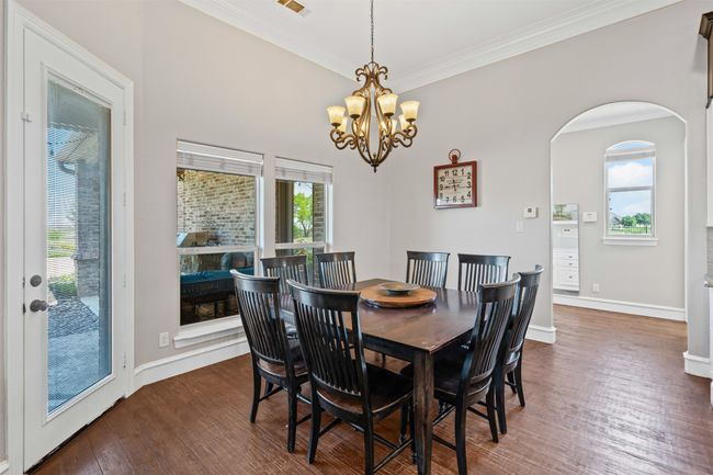 Dining area with an inviting chandelier, crown molding, dark wood-type flooring, a healthy amount of sunlight, and arched walkways | Image 17