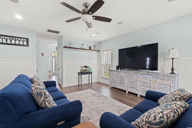 Living area on the first level featuring wainscoting, wet bar, speaker system, recessed lighting and an elevator. | Image 6