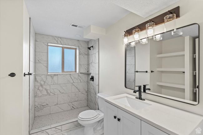 Full bath with a tile shower, toilet, vanity, marble finish floor, and visible vents | Image 20