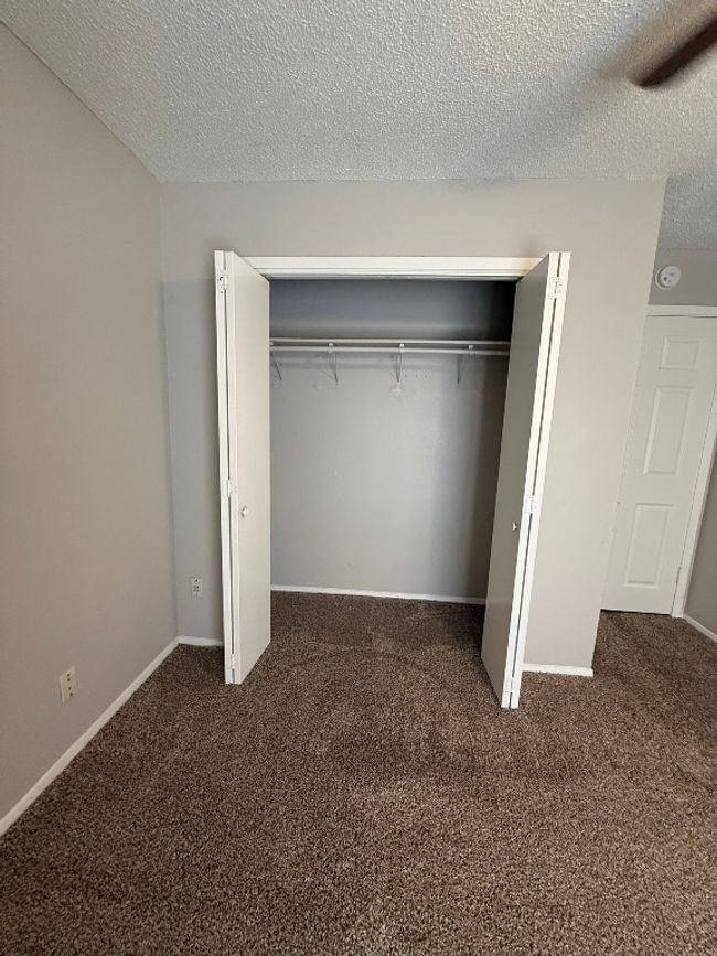 Unfurnished bedroom with a textured ceiling, carpet flooring, and a closet | Image 18