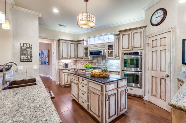 Kitchen with appliances with stainless steel finishes, a sink, light stone counters, dark wood-type flooring, and crown molding | Image 7