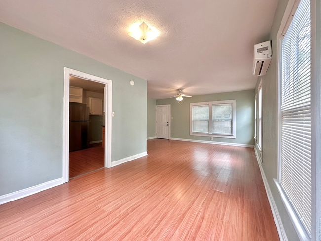 Unfurnished main room featuring an AC wall unit, a ceiling fan, and wood finished floors | Image 6