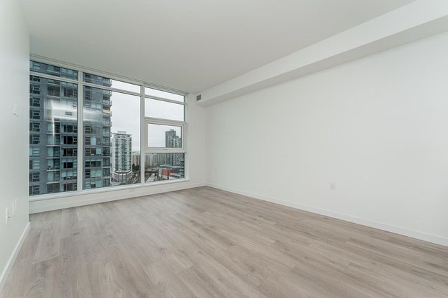 Spare room with light wood-type flooring, a view of city, and baseboards | Image 13