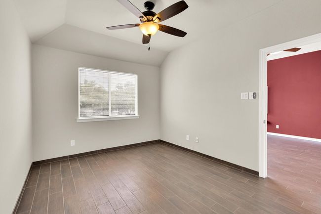 Unfurnished room featuring wood finished floors, lofted ceiling, baseboards, and ceiling fan | Image 21